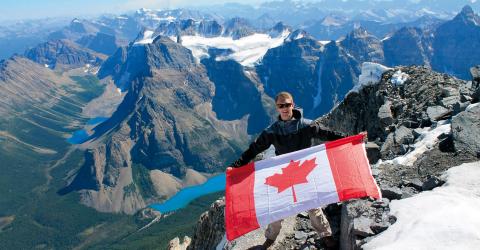 Junge mit kanadischer Flagge vor Bergpanorama 