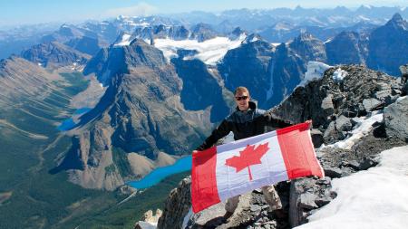 Junge mit kanadischer Flagge vor Bergpanorama 